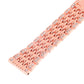 Rose gold metal watch band close-up with rhinestone-set links and patterned openings.