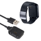 Smart watch on black charging cradle dock connected to USB-A cable