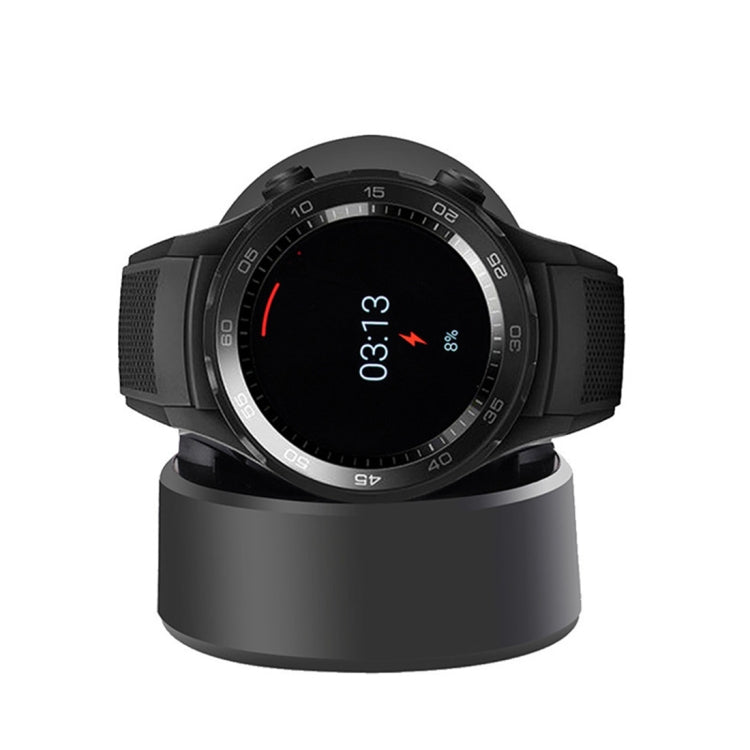 Black smartwatch resting on a round magnetic charging cradle base