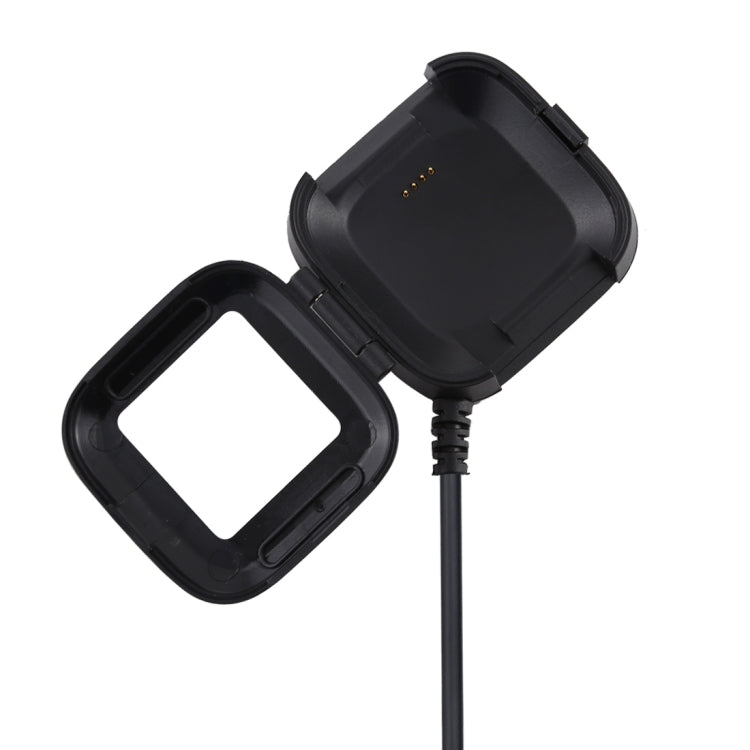 Black smartwatch charging cradle with attached cable and visible metal contacts
