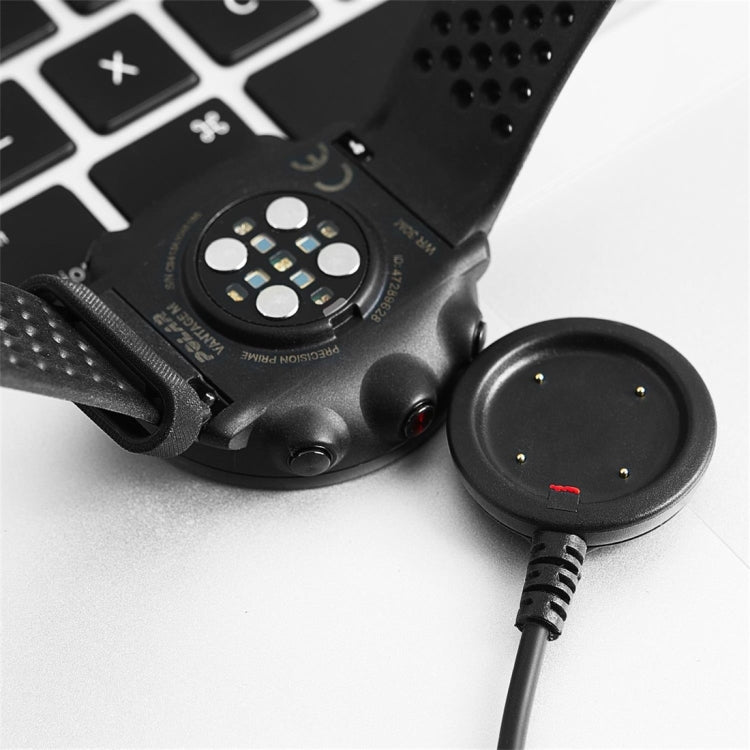 Smartwatch charging with round dock puck and connected cable, red indicator visible