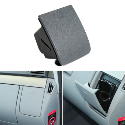 Grey dashboard co-driver cup holder cover with a pull slot, closed on the dash