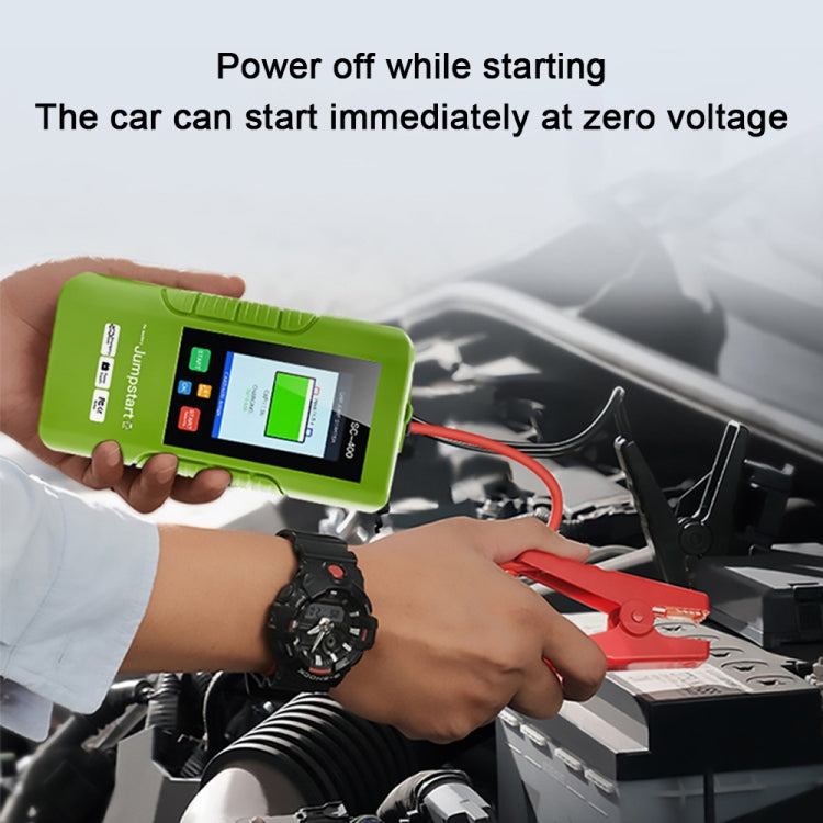 Green 12V jump starter held in hand with red/black clamps connected to car battery