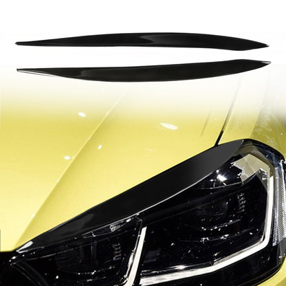 Pair of black headlight eyebrow stickers on a car headlamp, curved slim strips.