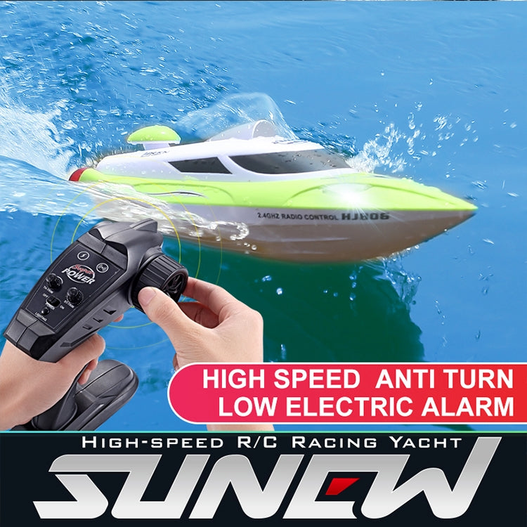 Green and white RC racing yacht with remote controller, cutting through water