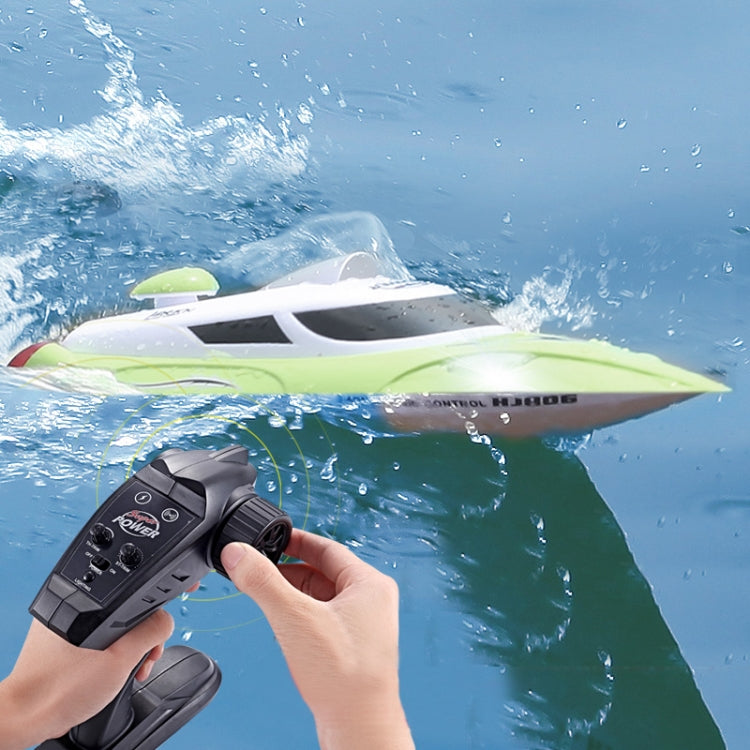 Green and white RC racing yacht with remote controller, close side view on water