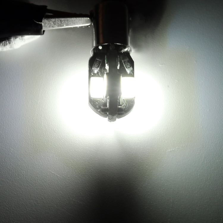 BA9S LED bulb glowing bright white, two yellow SMD chips visible inside the lens