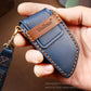 Blue leather key fob cover held in hand with stitched trim and metal ring