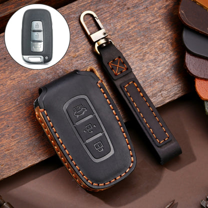 Black leather car key cover with protective 3-button remote outline and orange stitching