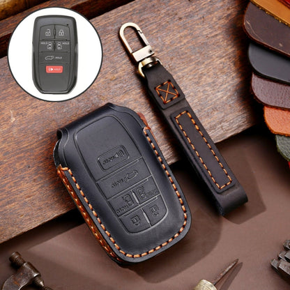Black leather key fob cover with button cutout and key ring strap, stitched edges.