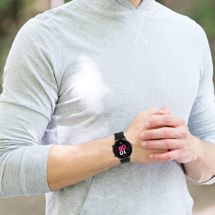 Black silicone watch strap on wrist with round watch case and buckle