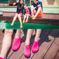 Pink slip-on water shoes on models seated by a pool