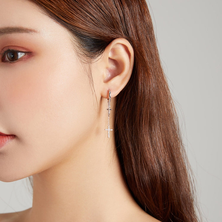 Woman wearing silver cross tassel earrings with long chain and cross charm drop