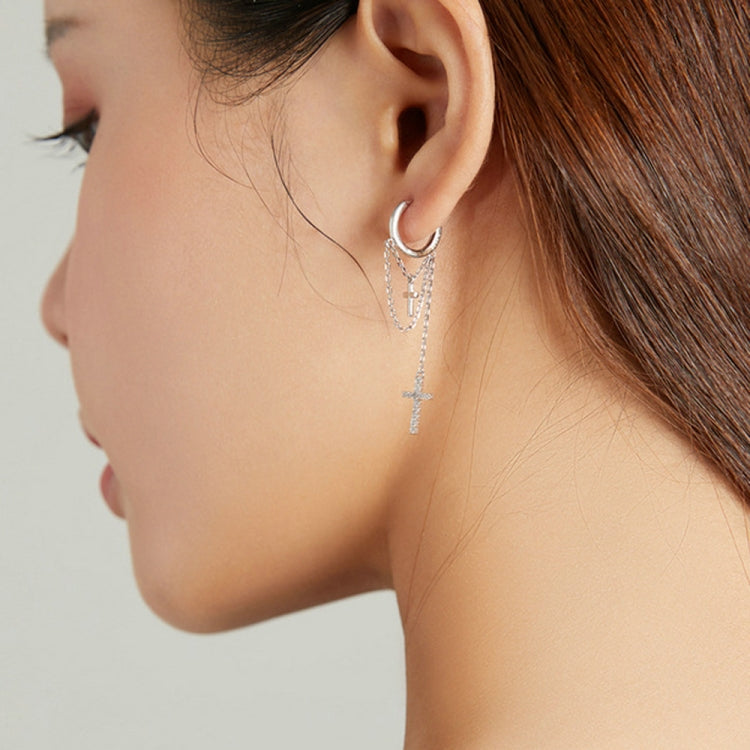 Profile view of silver cross tassel earrings with hoop ear cuffs and dangling cross chains
