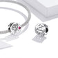 Two engraved silver charm beads with pink heart stones on a silver chain bracelet