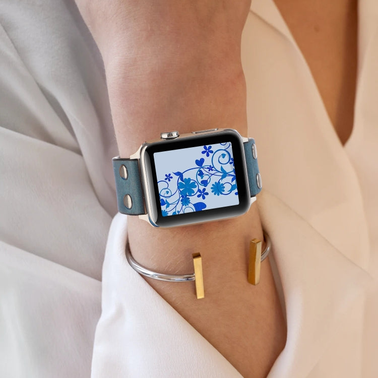 Blue leather watch band with metal buckle worn on wrist