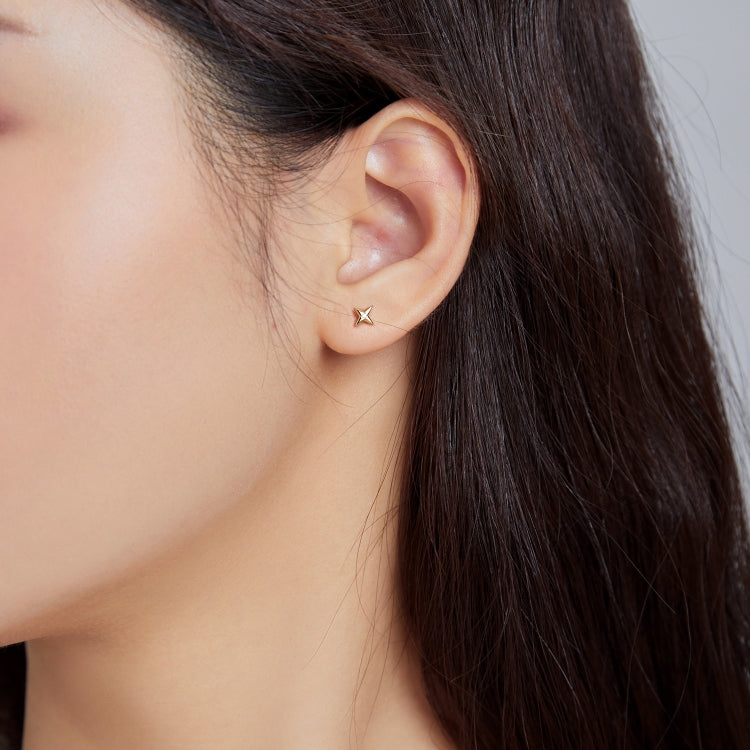 Close-up of gold star stud earrings on ear, featuring a small round CZ center.