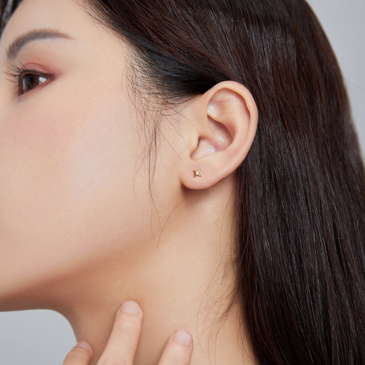 Side view close-up of gold star ear studs with tiny CZ center stone on earlobe.