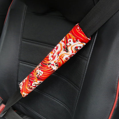 Car seat belt protective cover with red and white ornate swirl pattern.