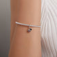 Silver snake-chain bracelet on wrist with small ladybug pendant charm in red and black