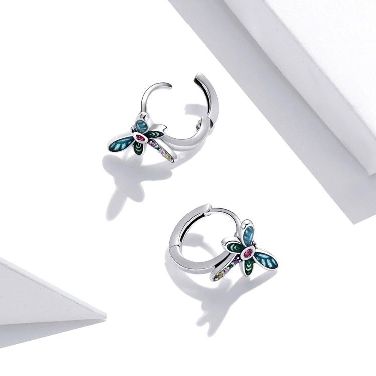 Pair of sterling silver dragonfly ear studs with blue wings, green accents, and pink center stone