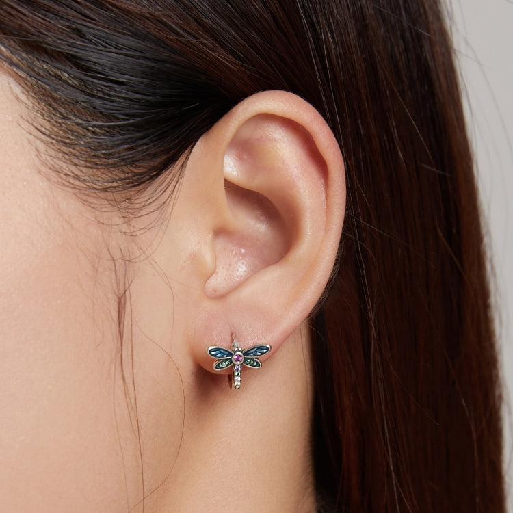 Dragonfly ear studs on a model: sterling silver with blue wings, green details, and pink gem