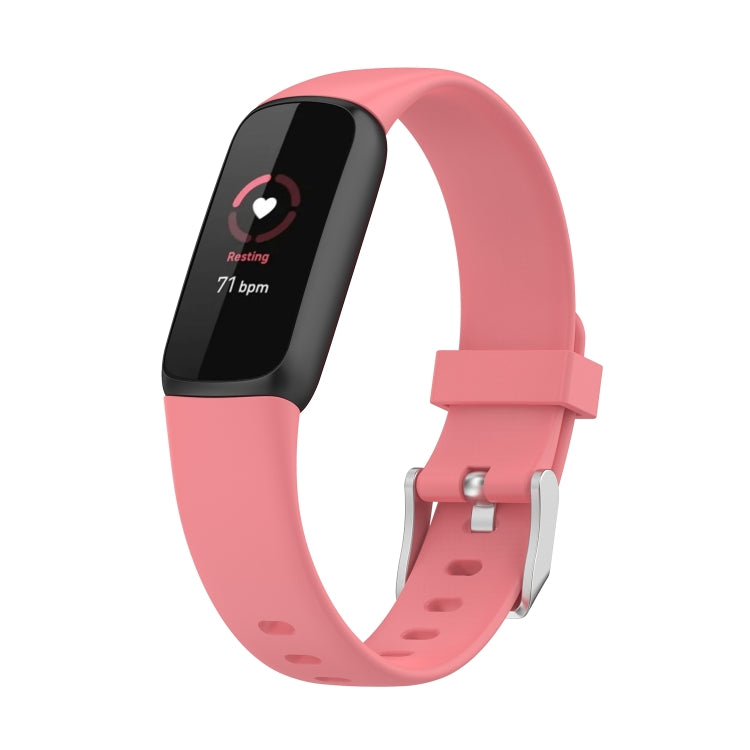 Pink silicone smartwatch band with buckle and perforations; dark fitness display shown.