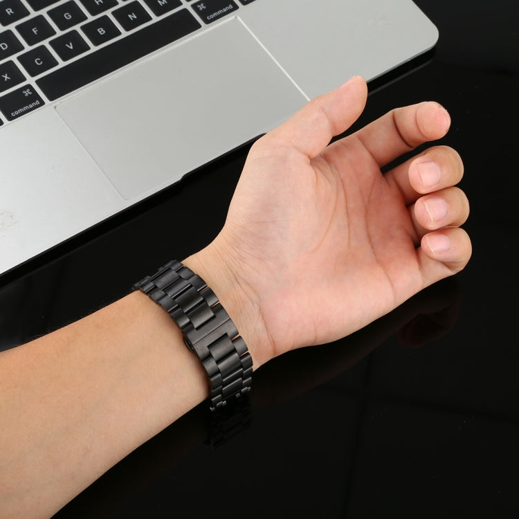 Black stainless steel Apple Watch link band on wrist, clasp and end holes visible