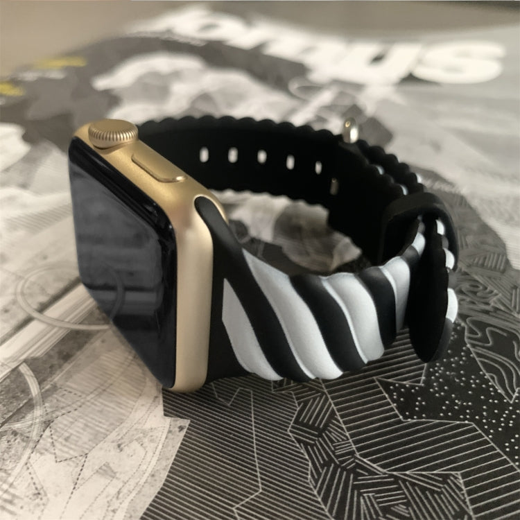 Two-tone silicone Apple Watch strap with black base, white stripes, and metal clasp