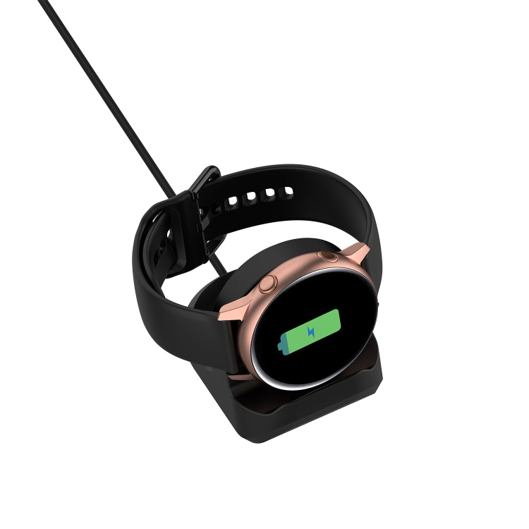 Black silicone charging stand holding a smartwatch in the cradle with charging cable