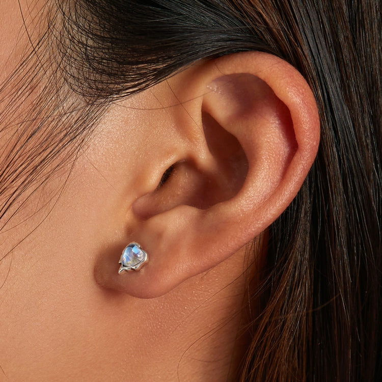 Blue heart-shaped moonstone stud earrings on ear close-up