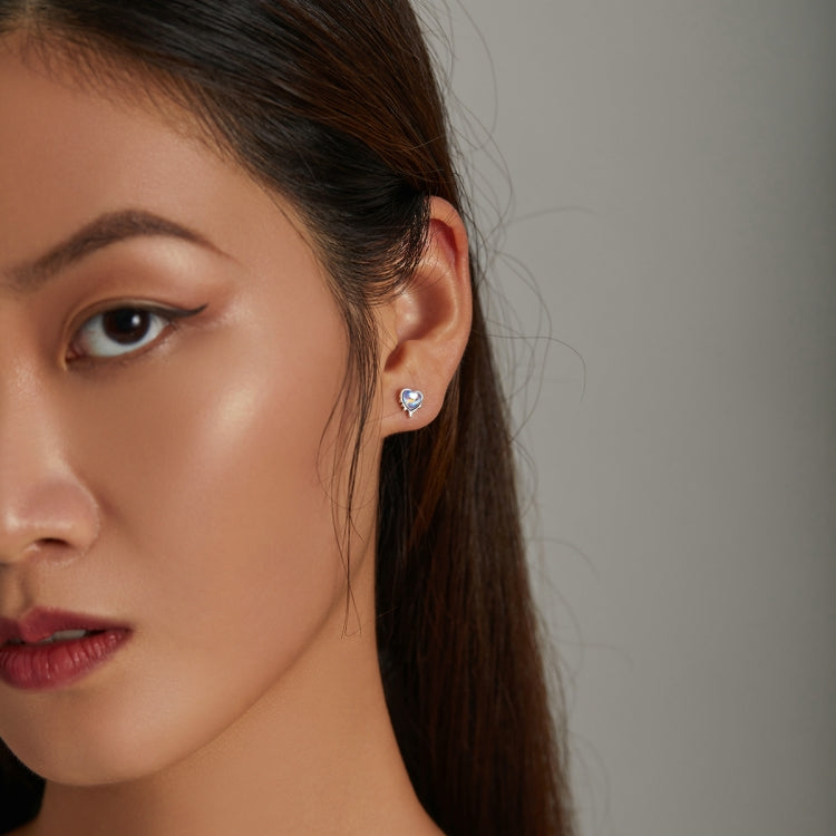 Heart moonstone stud earrings on model's ear with blue stone