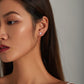 Pink flower stud earrings in sterling silver with tiny three-petal enamel blooms on ear