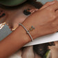 Sunflower charm bracelet on wrist with silver mesh band, yellow flower and green enamel leaves