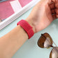Red nylon watch band with hook-and-loop closure worn on wrist