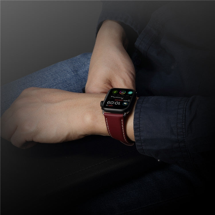 Hand wearing a red-brown leather watchband with metal clasp on the wrist