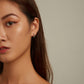 Sterling silver snake ear cuff earrings with green eye accents on model’s ear