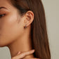 Model wearing silver snake ear buckles with green eye stones, small hoop cuff look