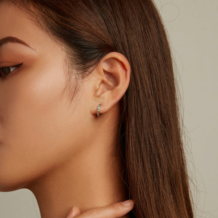 Sterling silver hoop earrings with small blue and green zircon stones on model