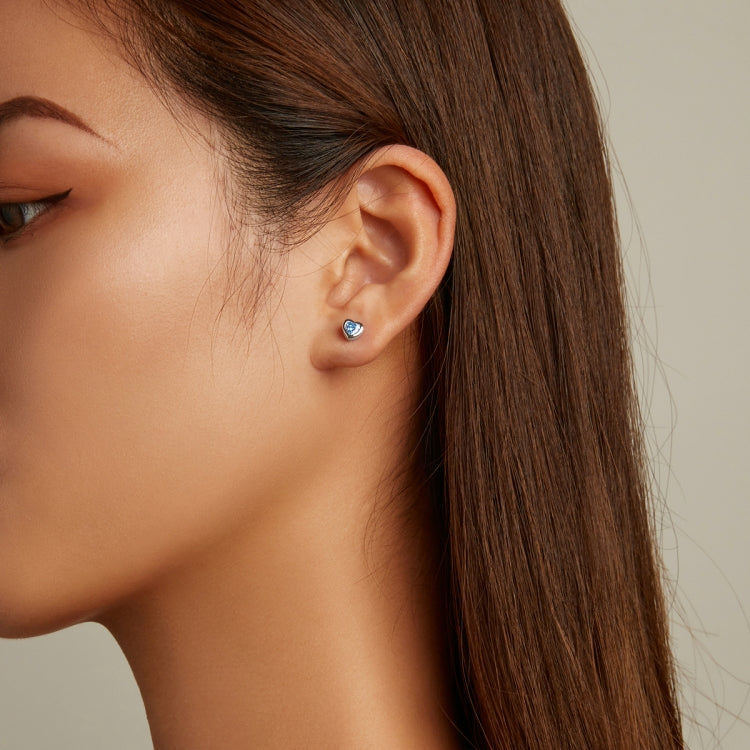 Small blue heart zircon stud earring on ear with silver backing