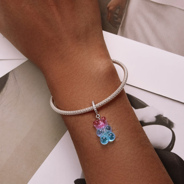 Wrist wearing silver bracelet with pink and blue resin candy bear pendant