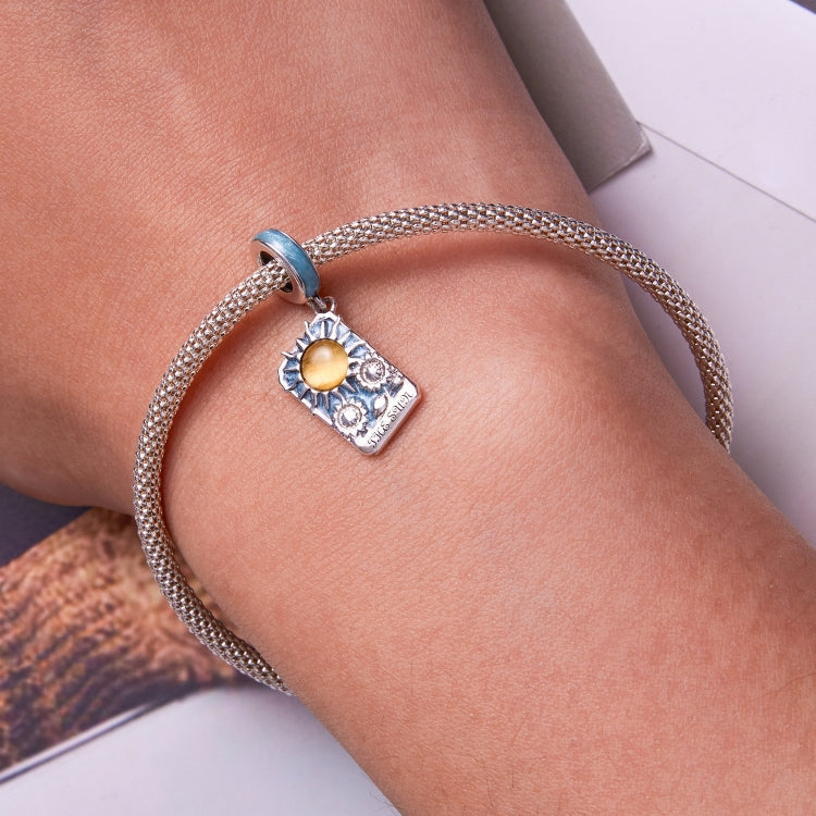 Sterling silver bracelet on wrist with mesh chain and tarot card sun charm in blue and yellow
