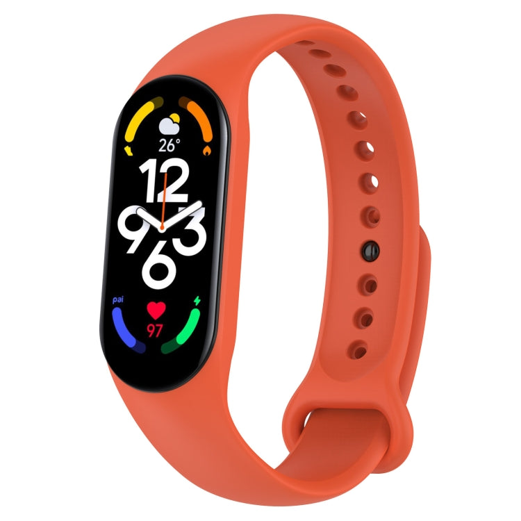 Orange silicone smartwatch band with perforation holes and pin clasp, tracker display visible.