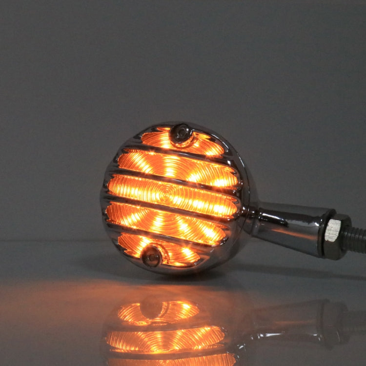 Lit amber retro LED turn signal with black housing and ribbed lens, single lamp.