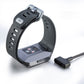 Charging cable plugged into a smartwatch dock, black band and cable end