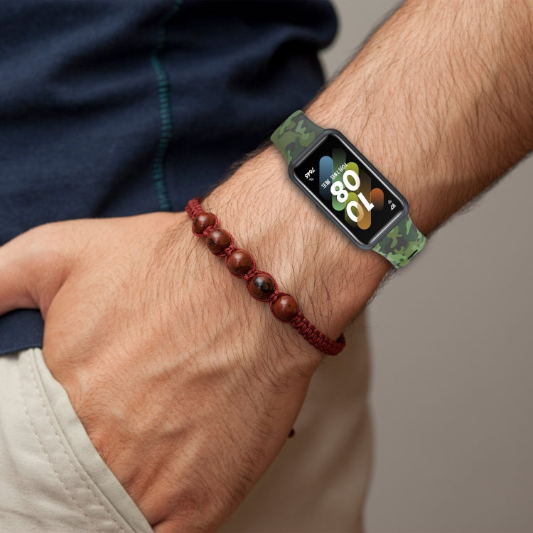 Green camouflage TPU watch band on wrist with perforated strap holes and metal buckle