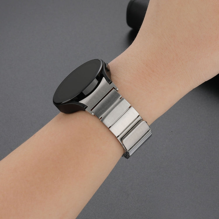 Magnetic steel watch band in silver on wrist, metal links with buckle-style clasp