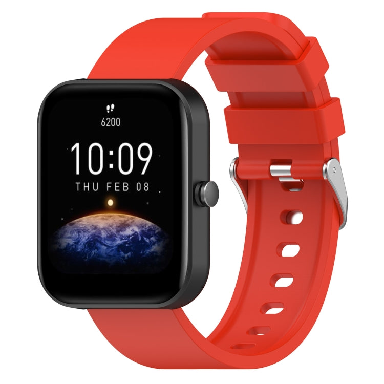 Red silicone watch band with metal buckle and adjustment holes, shown with matching smartwatch.