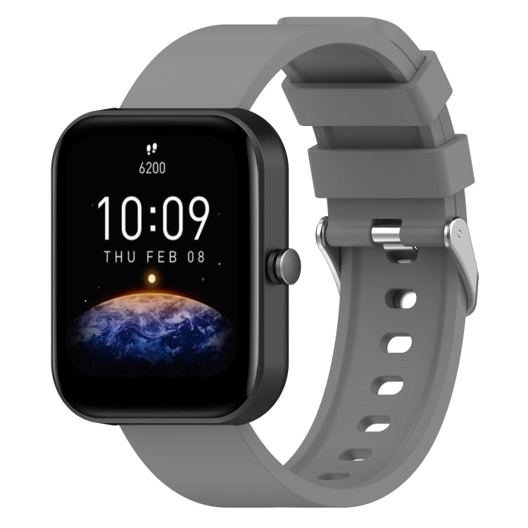 Grey silicone watch band with metal buckle and adjustment holes, shown with matching smartwatch.