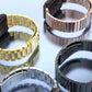 Close-up of metal watch band links in mixed colors, showing connector and clasp ends.